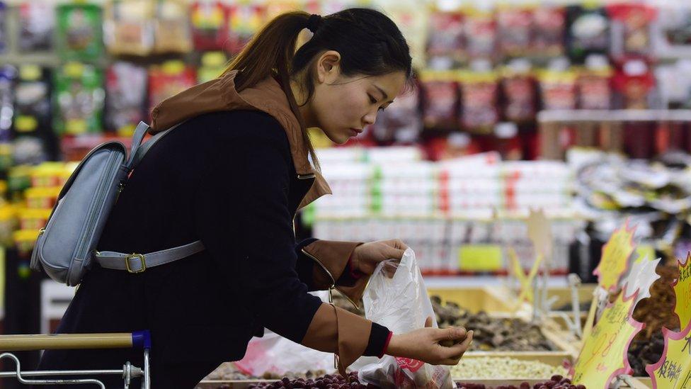 A woman selects dried longan at a supermarket in Fuyang, in eastern China's Anhui province on February 9, 2018.