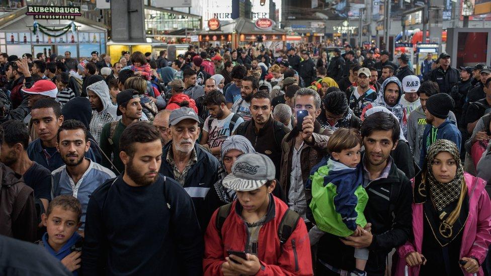 Refugees walk through the main train station in Munich, Germany