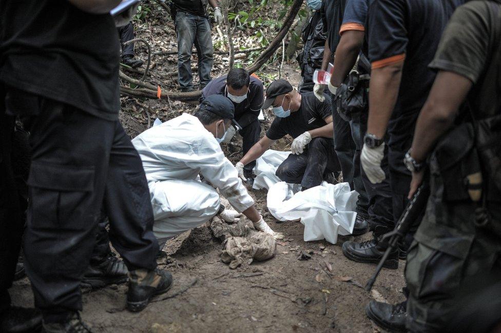 A Royal Malaysian Police forensic team handles exhumed human remains in a jungle at Bukit Wang Burma in the Malaysian northern state of Perlis, which borders Thailand, on 26 May 2015