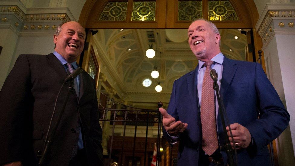 BC Green leader Andrew Weaver and BC New Democrat leader John Horgan react outside the gates of the British Columbia legislature building in Victoria, British Columbia, Canada