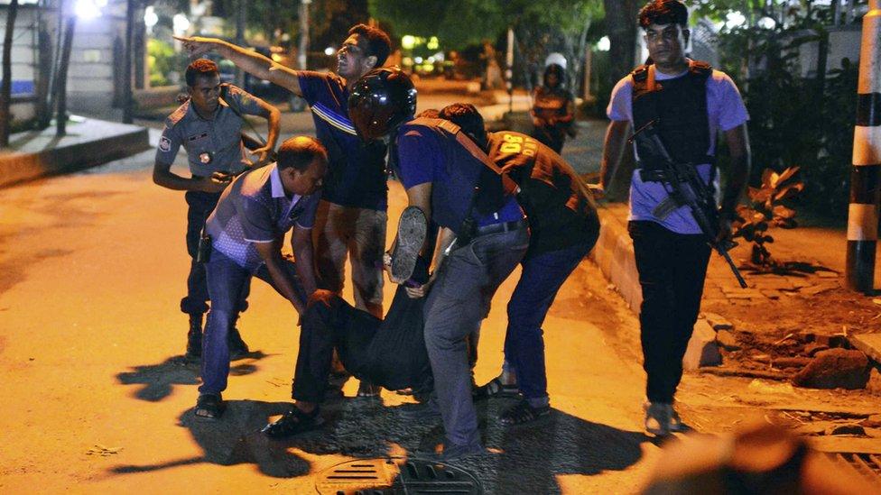 People help injured person after gunmen attack restaurant in Dhaka, Bangladesh, Friday, July 1, 2016