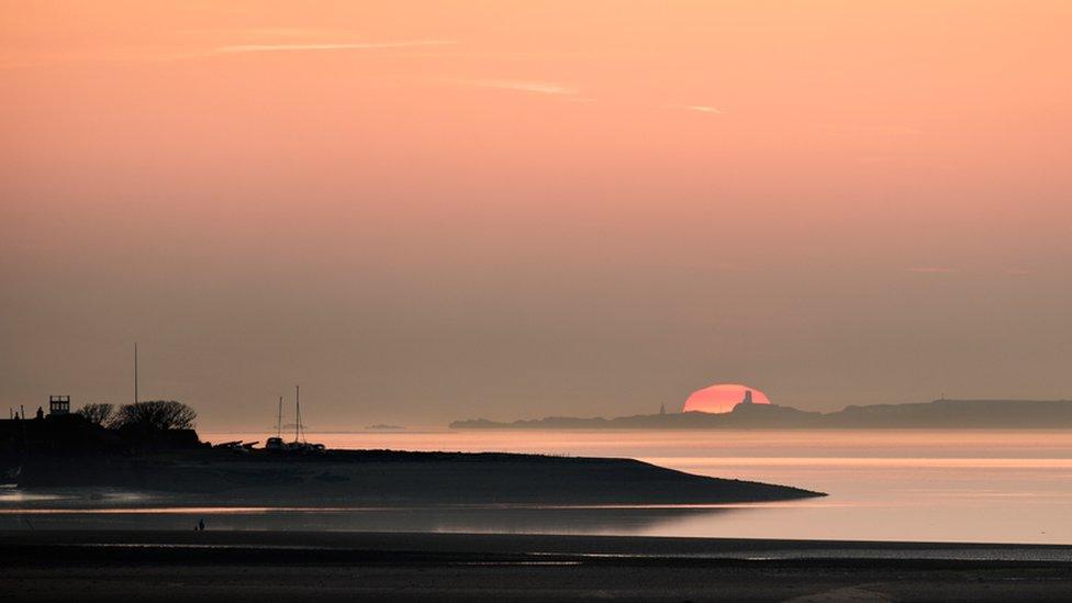 The sun setting behind Llanddwyn lighthouse on Anglesey