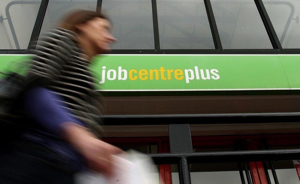 A woman walking past a job centre plus building.