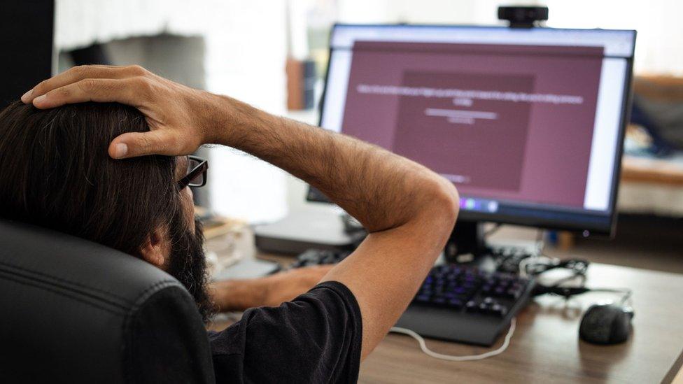 Aman in front of a computer at a work desk