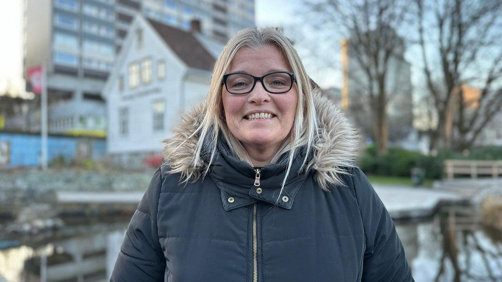 A woman with blond hair and glasses smiles at the camera