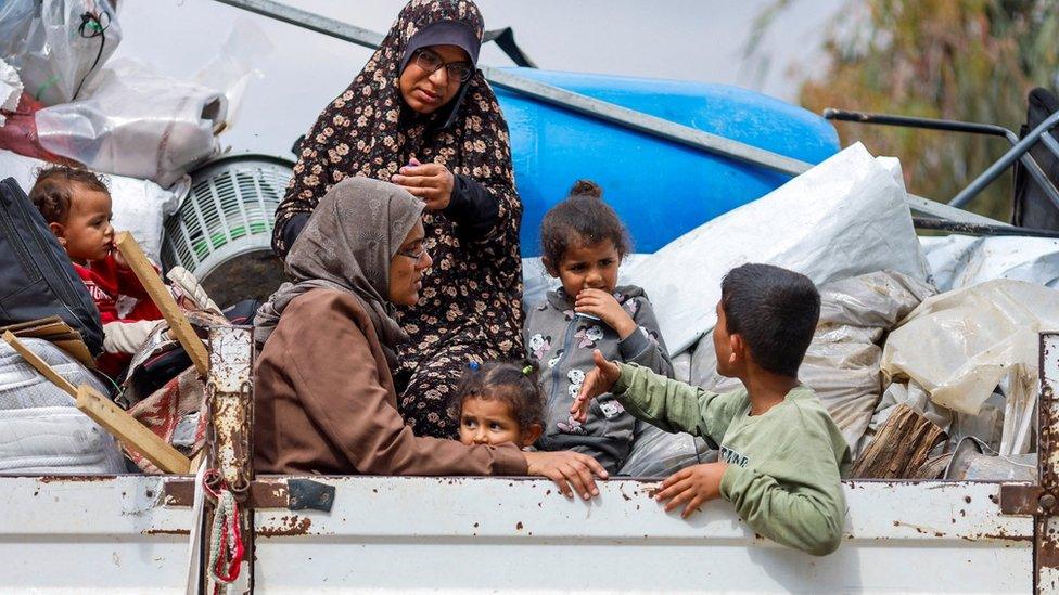 Palestinians ride in the back of a van as they flee Rafah, in the southern Gaza Strip (13 May 2024)