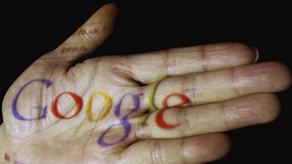 The Google logo is seen projected onto the palm of a hand on