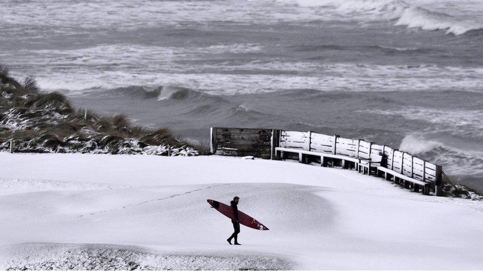 Professional surfer Alastair Mennie makes his way towards the beach at Portrush in Antrim, Northern Ireland