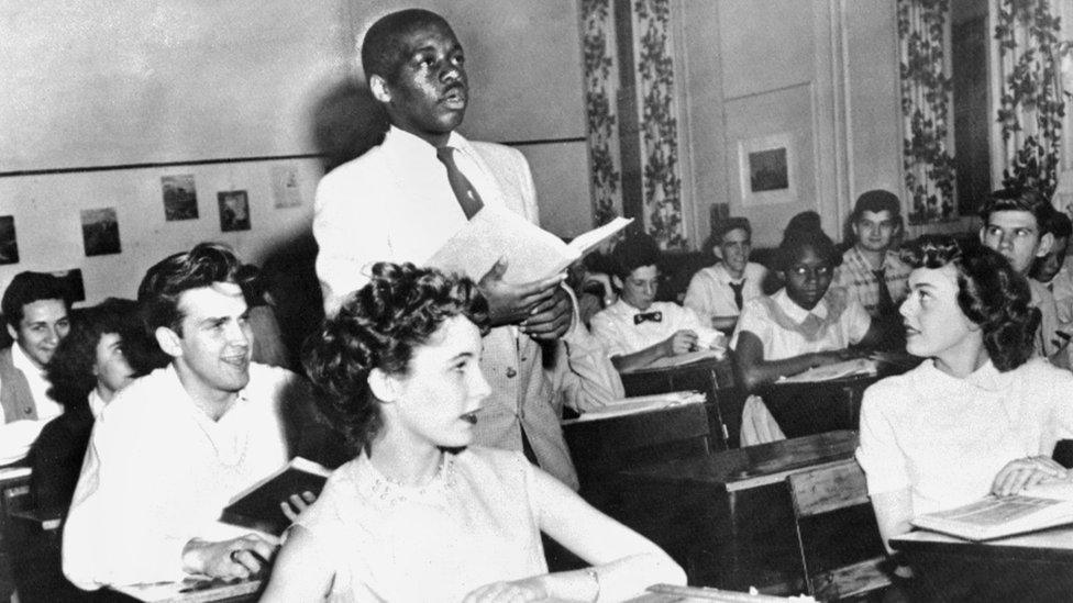 A black student, Nathaniel Steward, 17, recites his lesson surrounded by white fellows and others black students, 21 May 1954 at the Saint-Dominique school, in Washington, where for the first time in USA the Brown v Board of Education decision which outlaws segregation in state schools is applied.