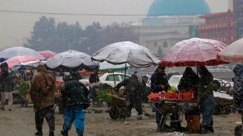 Snow falls at a market in Kabul