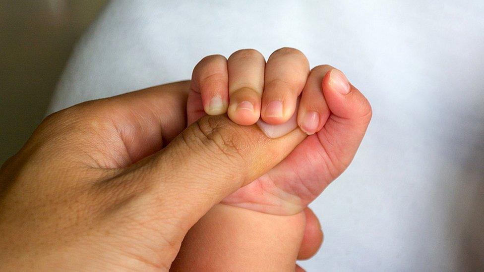 Mother holds baby's hand (close up)