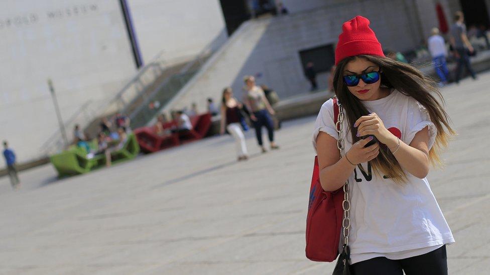 A woman in Vienna walking along while looking at a mobile phone