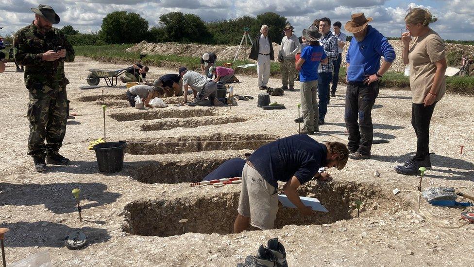 People standing in very old graves looking at objects