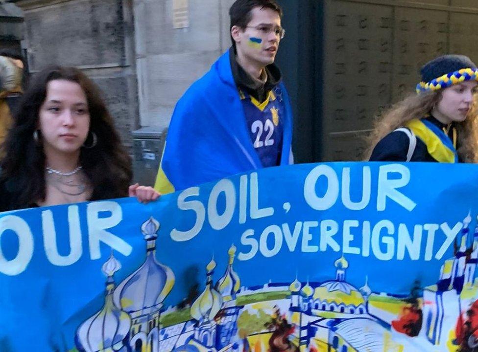 Tomas marches with other Ukraine supporters holding a banner that reads: Our soil, our sovereignty