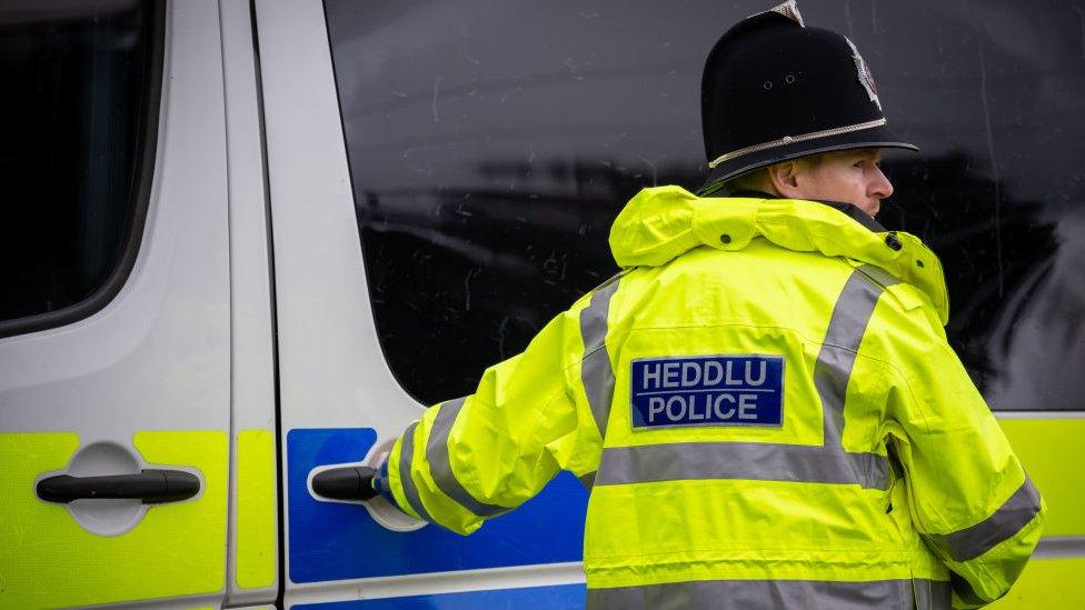 Welsh police officer holding a door handle of a police van