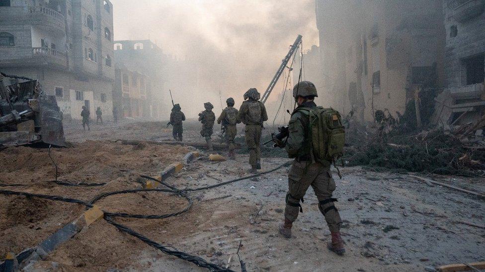 Israeli soldiers walk through rubble in the Gaza Strip