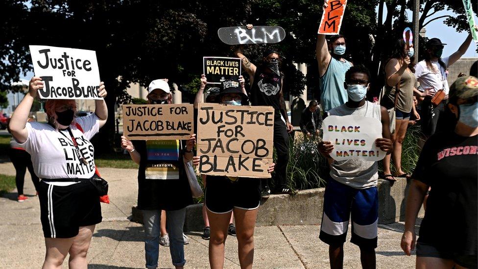 People hold placards as they gather for a protest outside the Kenosha County Courthouse