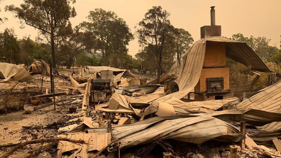 Twisted corrugated iron and brick stacks remain of a home destroyed by fire in Mallacoota