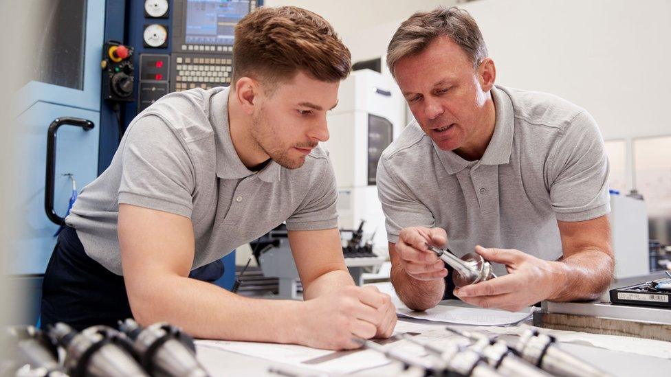 Engineer Showing Apprentice How To Measure CAD Drawings