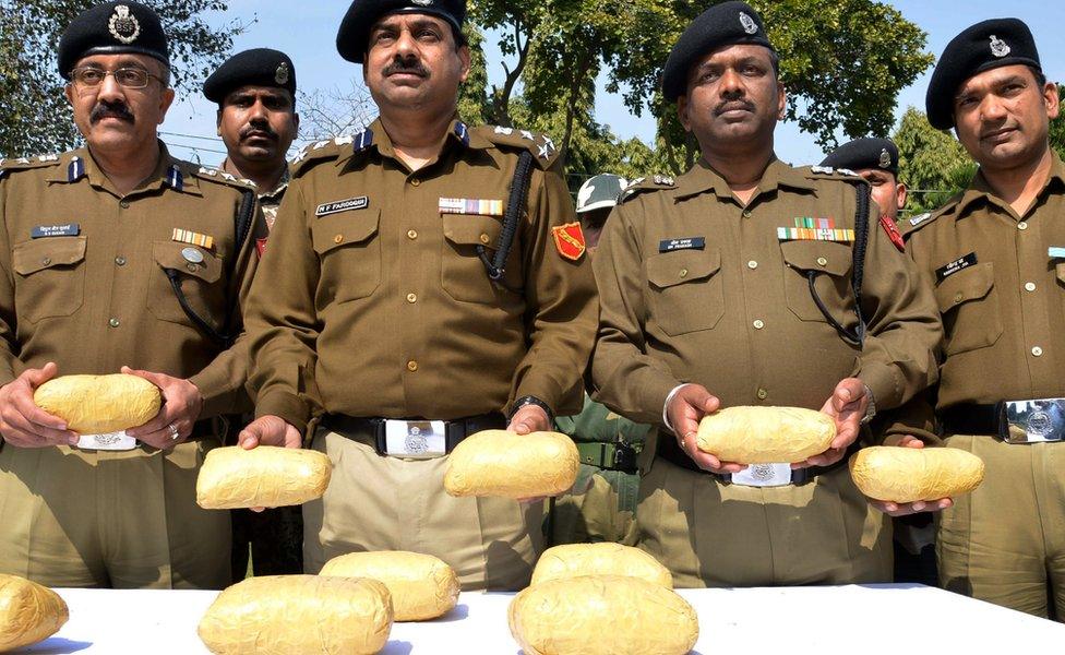 Indian Border Security Force (BSF) Deputy Inspector General MF Farooqui (C) poses for a photograph while holding confiscated parcels of heroin, recovered near the border with Pakistan, at the BSF headquarters in Khasa, some 20 kms west of Amritsar on February 24, 2014.