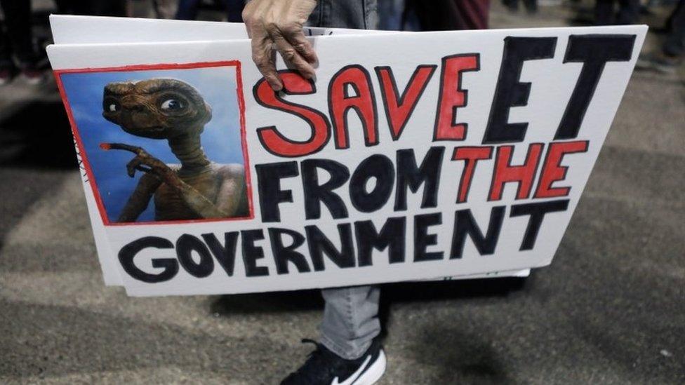 A person carries signs outside a gate to Area 51