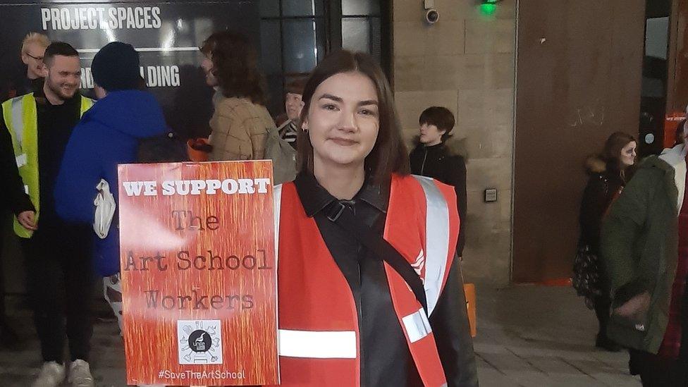 Anya Bowcott holding a sign outside the GSASA bar during the protest