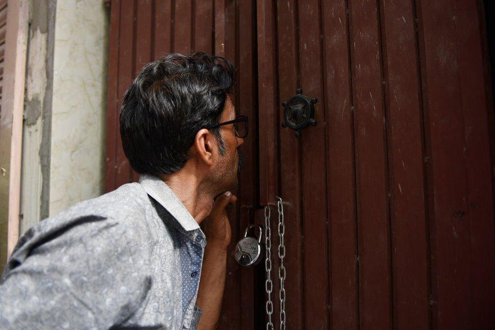 A man peeps inside the house where 11 members of a family allegedly committed suicide on 2 July in Delhi.