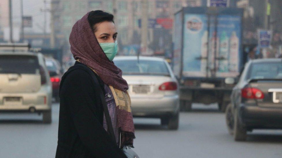 An Afghan woman wears a face mask as she walks in a busy Bazar in Kabul, Afghanistan on December 23, 2020