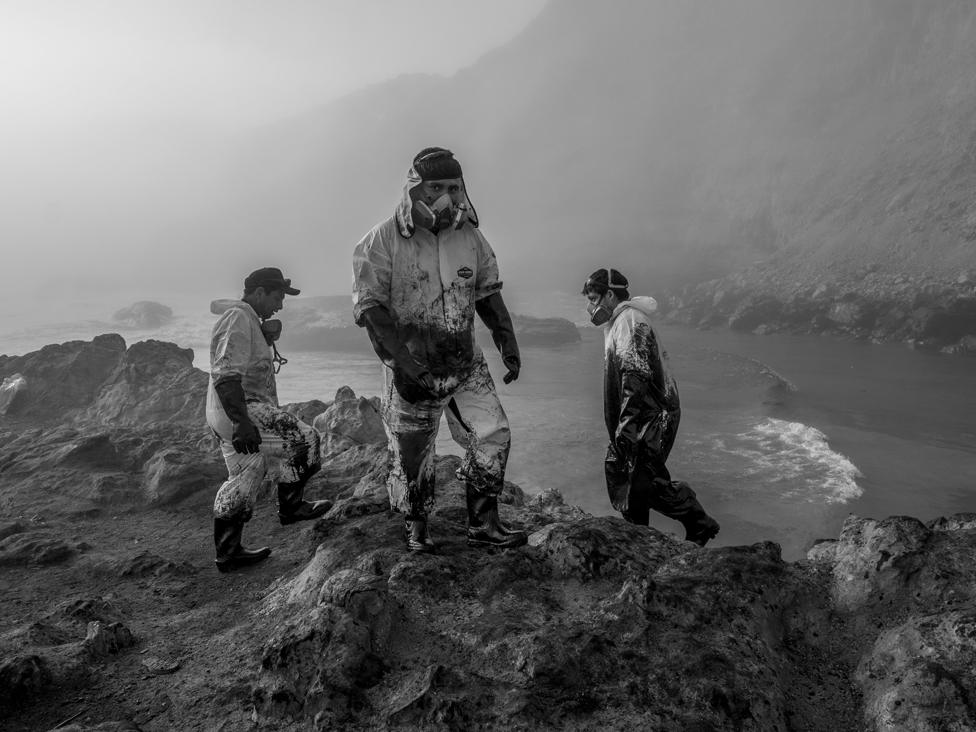 Workers deal with the environmental disaster caused by an oil spill at Repsol's nearby La Pampilla refinery at Playa Cavero, Peru, 21 January 2022