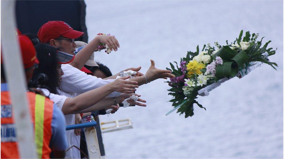 Relatives of victims of AirAsia flight QZ8501 throw a flower wreath into the sea in Central Kalimantan on 22 March 2015