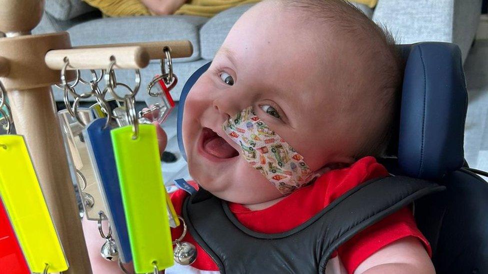 Drae smiling at the camera while playing with toys