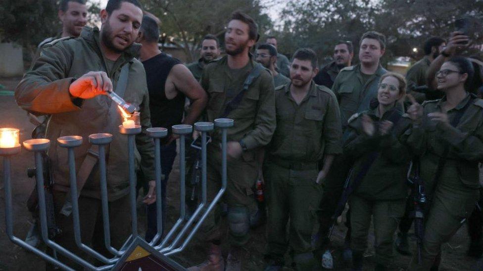 An Israeli soldier lights the first candle at a position near the Gaza border, amid continuing battles between Israel and Hamas