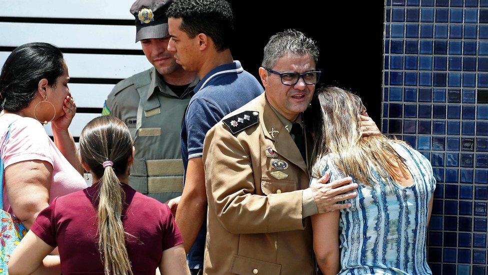 Police comfort a woman at the scene of the shooting