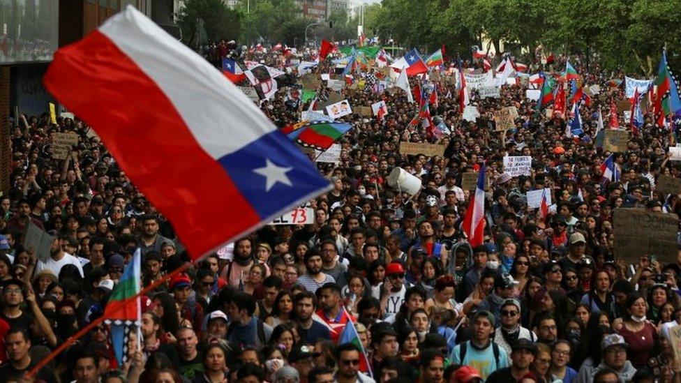 Demonstrators march with flags and signs during a protest against Chile"s state economic model in Santiago, Chile October 25, 2019