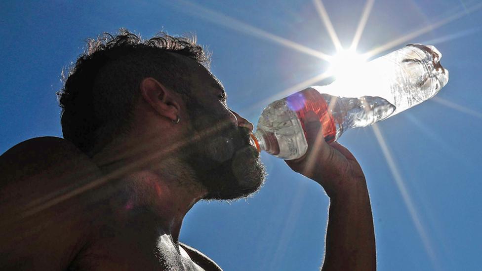 A man drinks water on Copacabana Beach in Rio de Janeiro, Brazil, 19 September 2023, during a heatwave