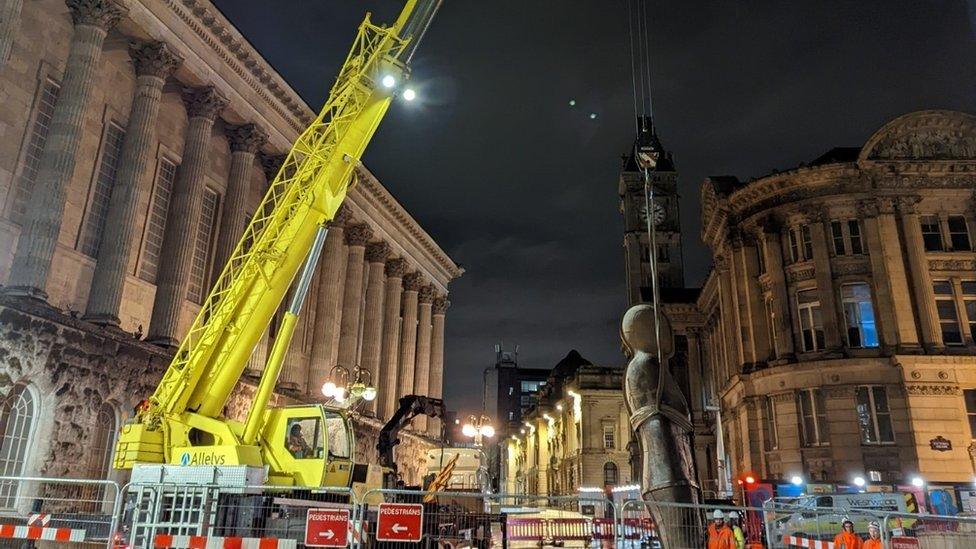 The statue being lowered by a crane into position