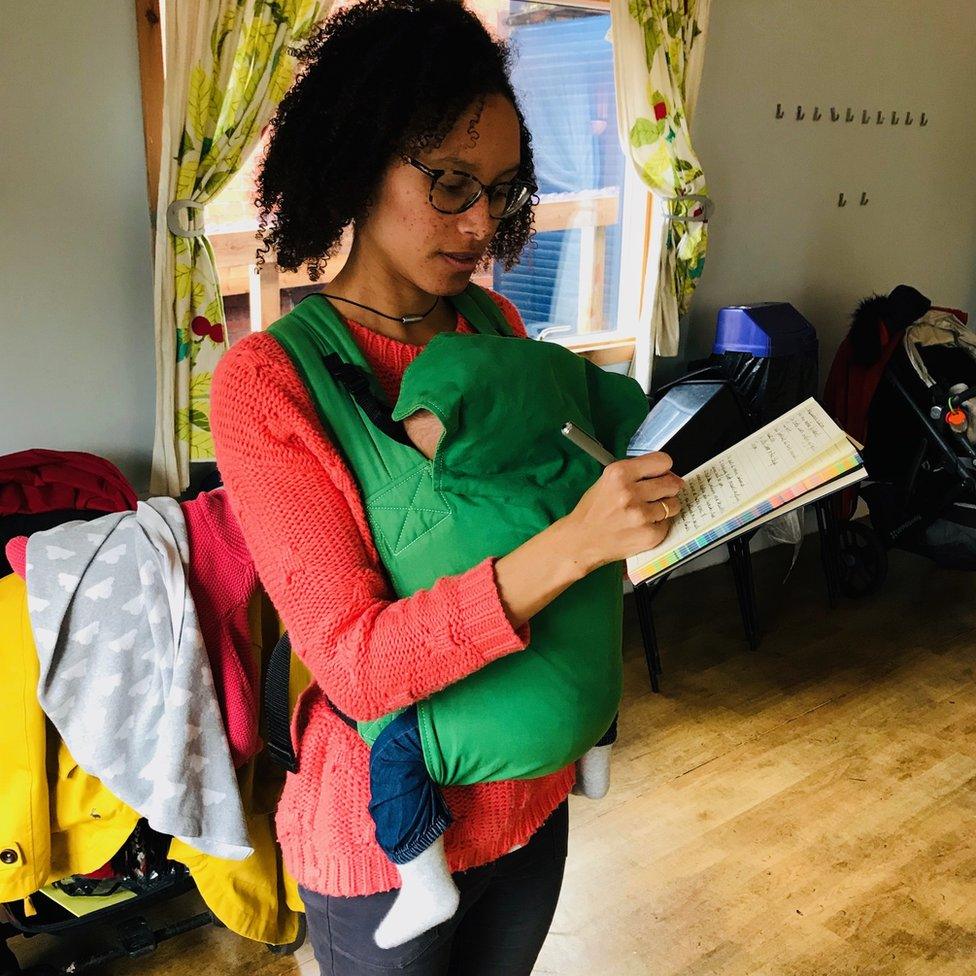 Woman writing with baby in sling