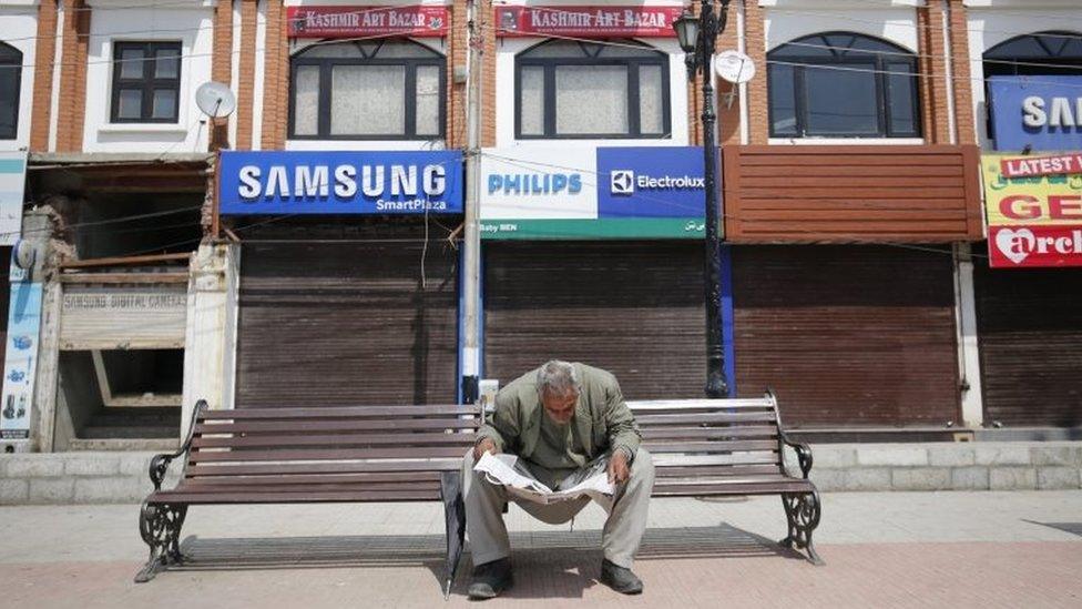 A man reads a newspaper in front of a closed market during a shutdown in Srinagar, the summer capital of Indian Kashmir, 12 April 2016.