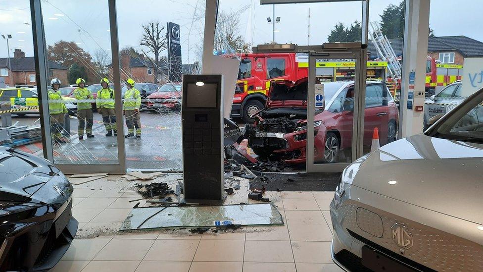 Damaged car after crashing into glass showroom building