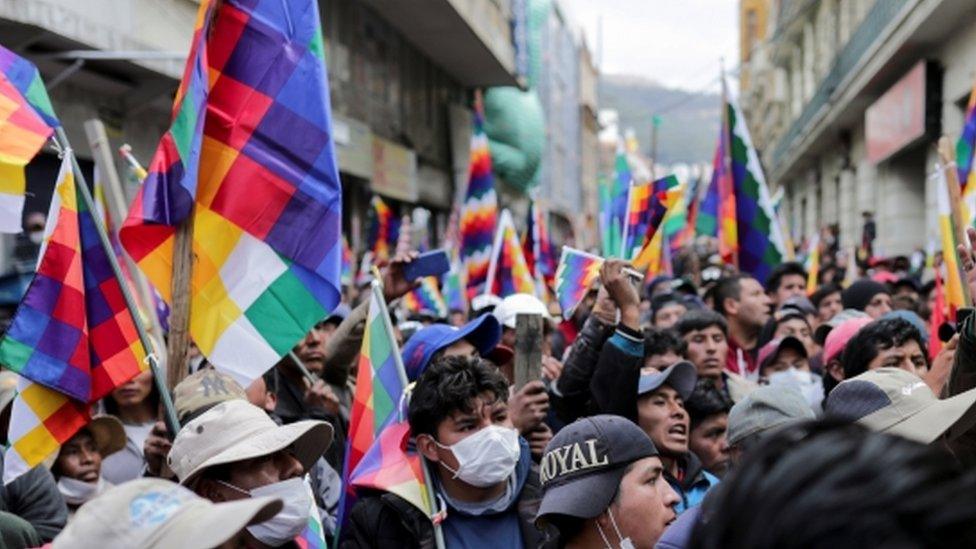 A crowd of protesters waved the multicoloured Wiphala flag