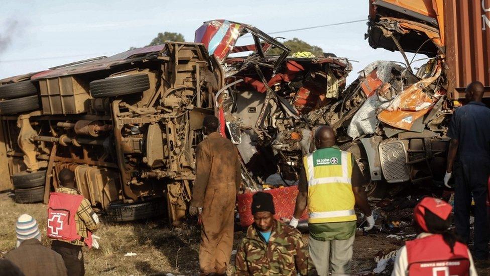 The bus wreckage is pictured on its side, heavily damaged, surrounded by emergency workers