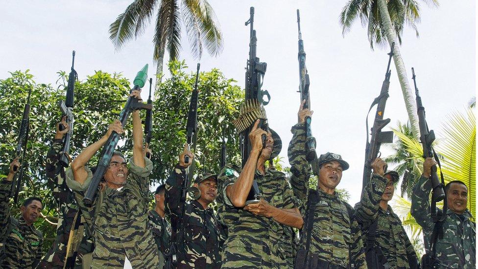 Muslim guerrillas of the Moro Islamic Liberation Front (MILF) raise their weapons during a formation in Camp Darapanan