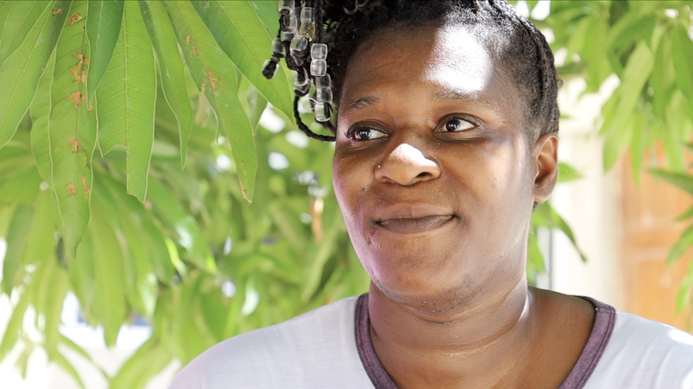 Hairdresser Sherica Bourn pictured against a leafy backdrop, her hair braided with beads