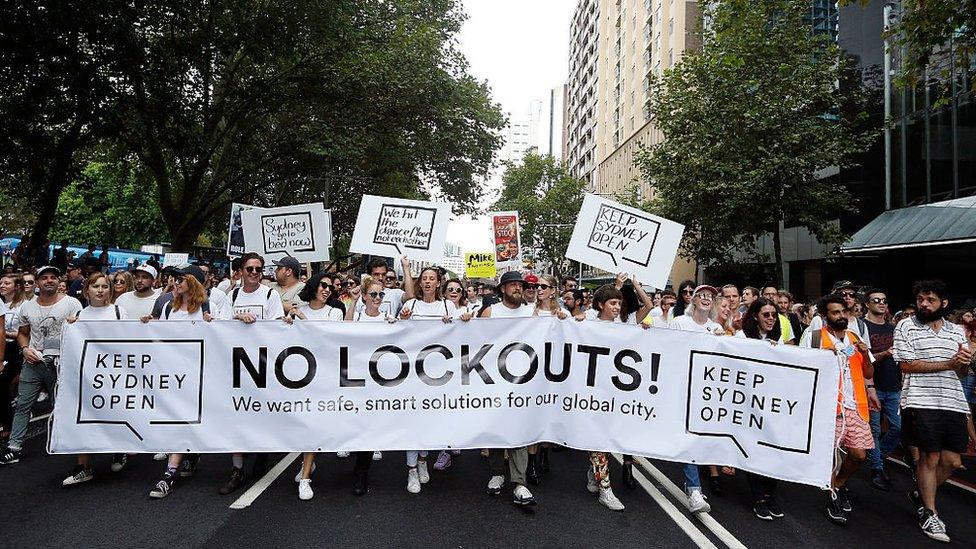 Protesters hold a sign saying: "Keep Sydney open. No lockouts! We want safe, smart solutions for our global city".