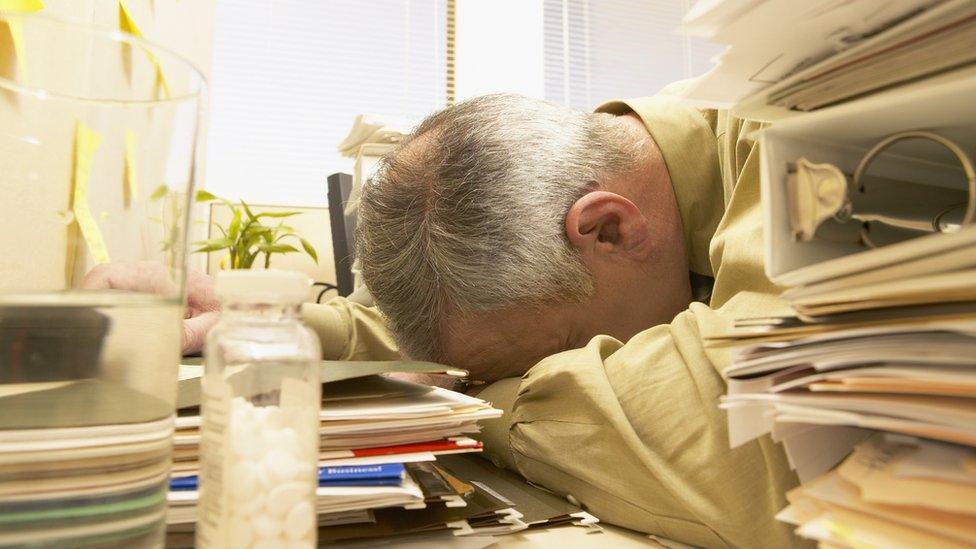 Overworked man asleep at messy desk