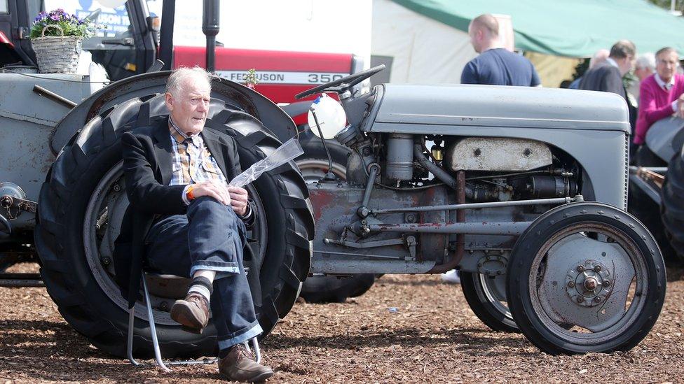 A man sits beside a vintage tractor at Balmoral Show