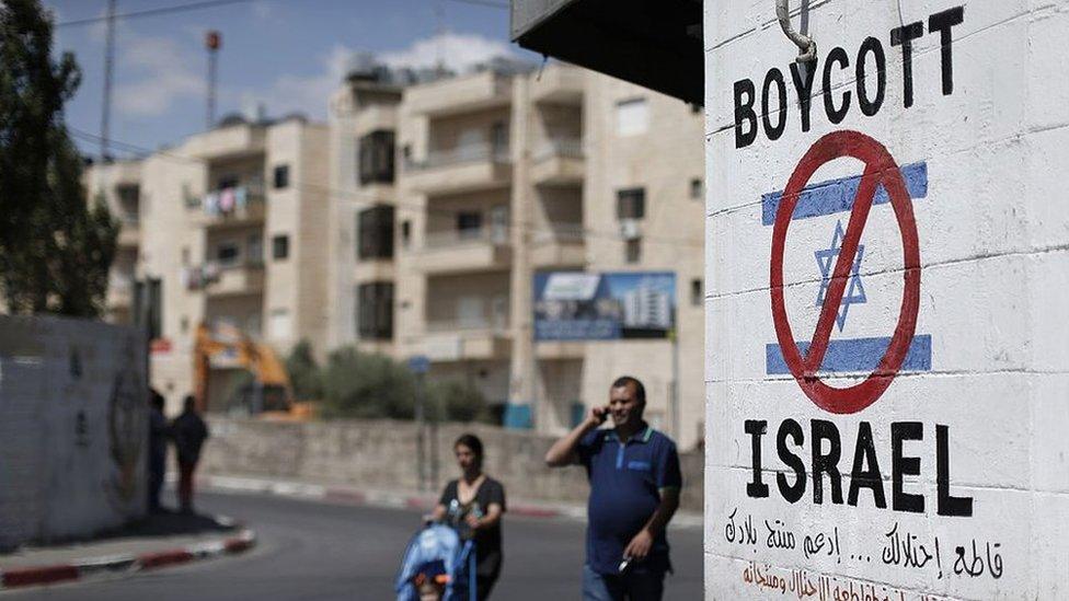 A tourist photographs a sign painted on a wall in the West Bank biblical town of Bethlehem on 5 June 2015, calling to boycott Israeli products coming from Jewish settlements