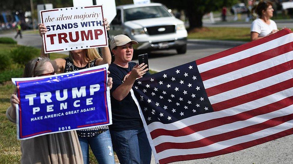 Trump supporters hold a US flag and a sign saying "the silent majority stands with Trump"