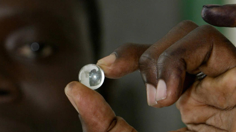 A voter in Gambia holding up a marble used to vote - archive shot