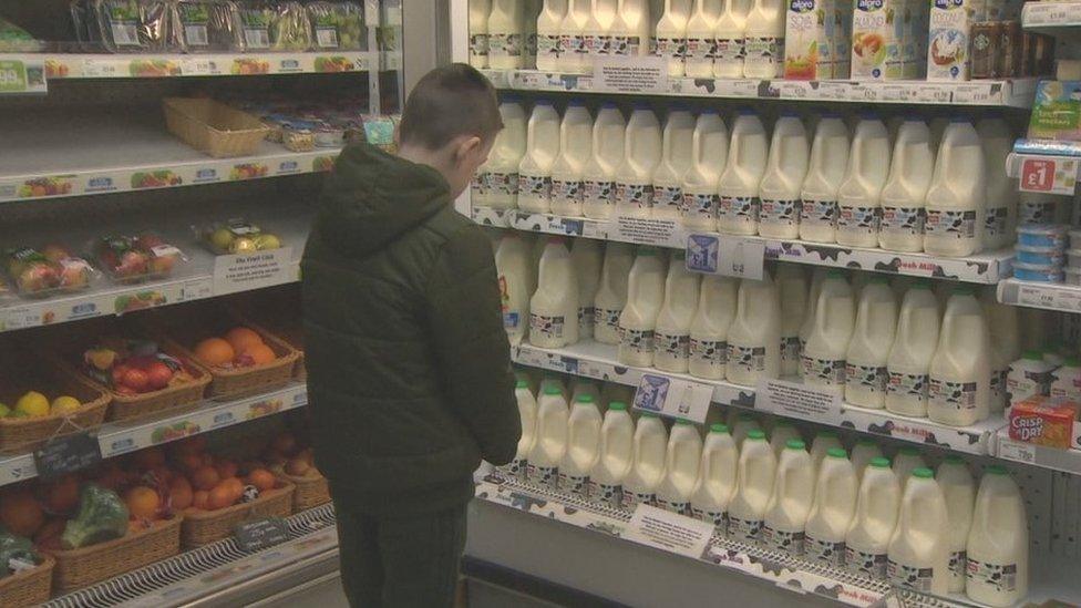 Boy standing in front of milk cartons